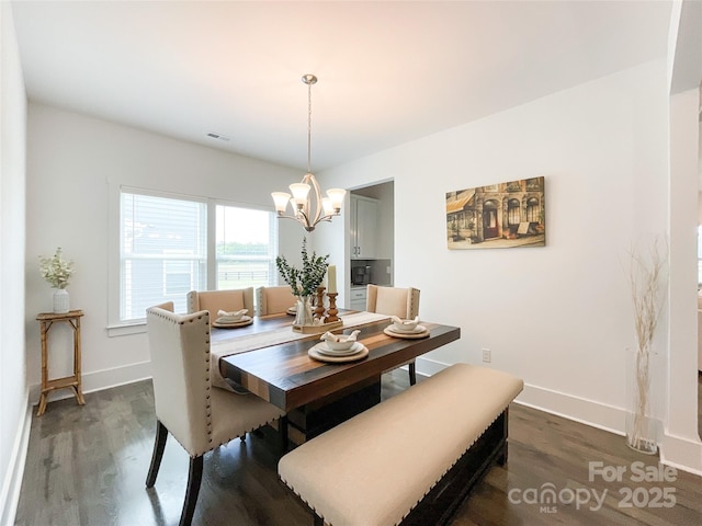 dining area featuring dark wood-type flooring, a chandelier, and baseboards