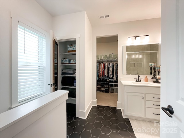 bathroom with a stall shower, a walk in closet, vanity, and tile patterned flooring