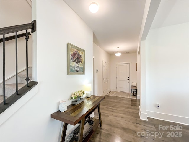 hall with dark wood-style floors, baseboards, and stairs