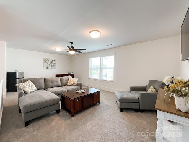living area featuring light colored carpet and a ceiling fan