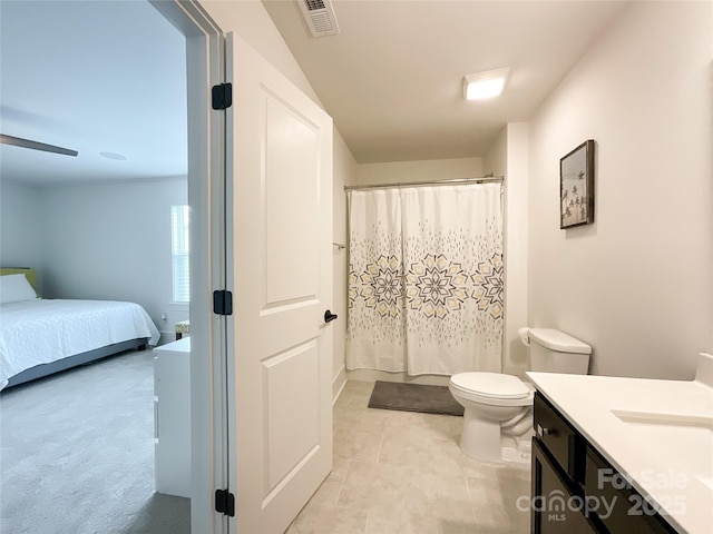 ensuite bathroom featuring toilet, a shower with shower curtain, vanity, and tile patterned floors