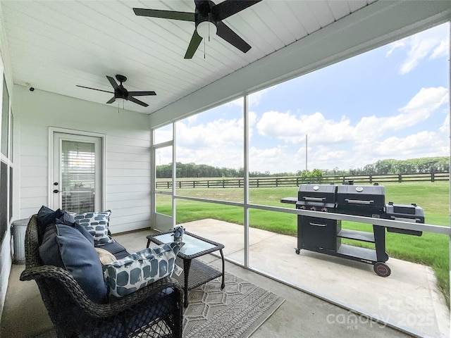 sunroom / solarium featuring a ceiling fan and a view of rural / pastoral area