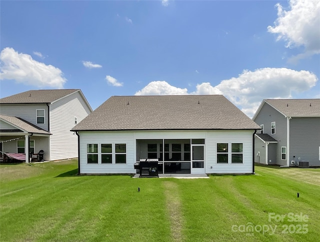 rear view of property with a yard, roof with shingles, and cooling unit
