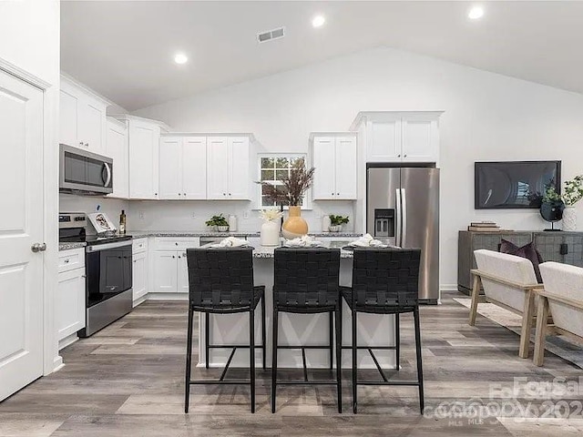 1604 N Main St, Mount Holly, NC 28120 - kitchen featuring appliances with stainless steel finishes, a kitchen bar, a kitchen island, white cabinets, and recessed lighting