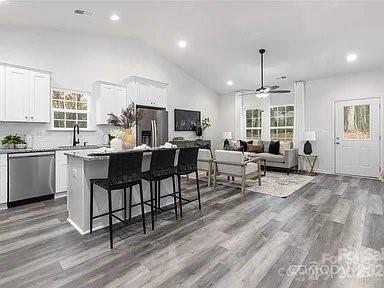1604 N Main St, Mount Holly, NC 28120 - kitchen featuring stainless steel appliances, a center island, healthy amount of natural light, wood finished floors, and lofted ceiling