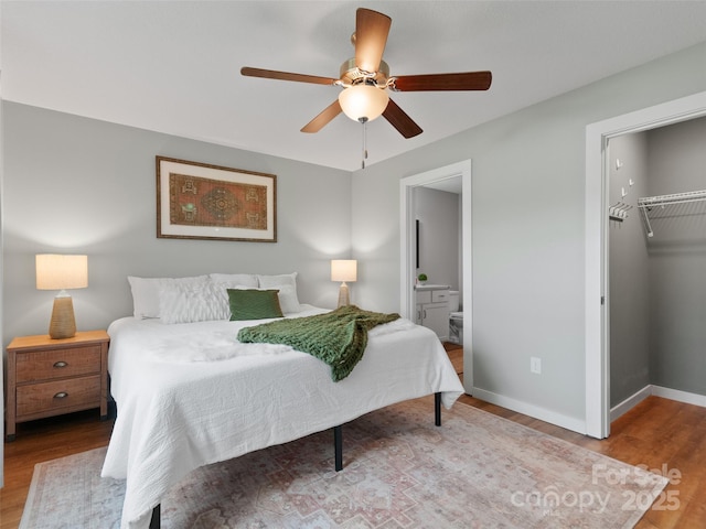 128 Lewis Ln, Candler, NC 28715 - bedroom featuring wood finished floors, a closet, a spacious closet, ensuite bathroom, and a ceiling fan