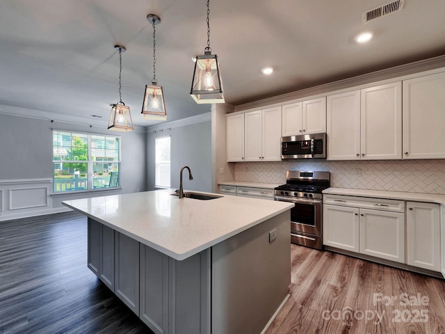2001 Laurel Village Cir, Belmont, NC 28012 - kitchen featuring a sink, appliances with stainless steel finishes, ornamental molding, wood finished floors, and white cabinetry