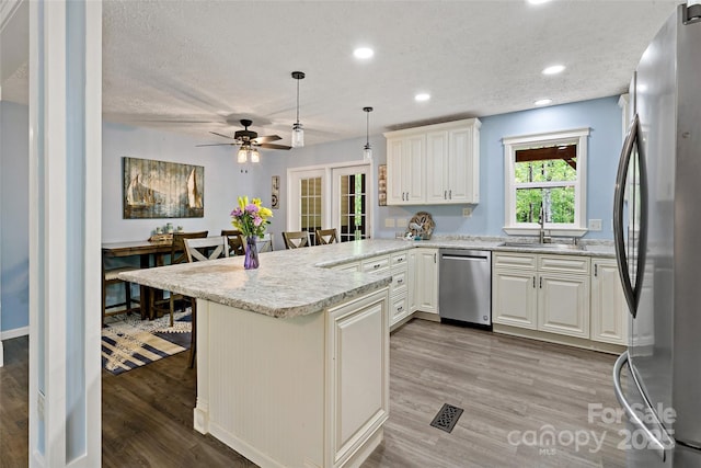 174 Sassafras Hill Dr Unit 41, Rutherfordton, NC 28139 - kitchen with stainless steel appliances, a sink, a peninsula, light wood-style flooring, and a kitchen bar