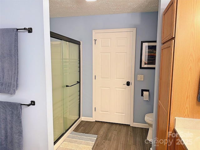 174 Sassafras Hill Dr Unit 41, Rutherfordton, NC 28139 - bathroom featuring wood finished floors, a stall shower, toilet, baseboards, and a textured ceiling