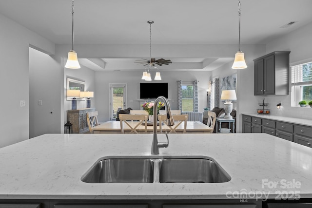7604 Tanglewood Way, Denver, NC 28037 - kitchen featuring gray cabinetry, a ceiling fan, hanging light fixtures, light stone countertops, and a tray ceiling