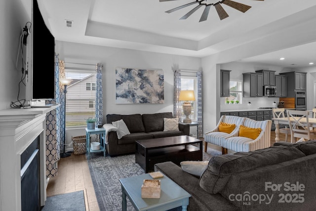 7604 Tanglewood Way, Denver, NC 28037 - living room with ceiling fan, a tray ceiling, hardwood / wood-style floors, a fireplace, and recessed lighting