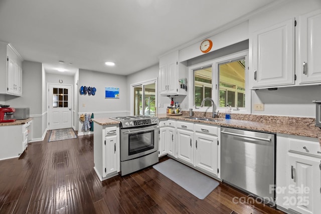 kitchen with appliances with stainless steel finishes, a sink, a peninsula, white cabinets, and recessed lighting