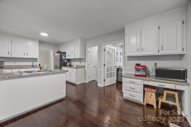 kitchen featuring appliances with stainless steel finishes, white cabinets, recessed lighting, light stone counters, and dark wood-style flooring