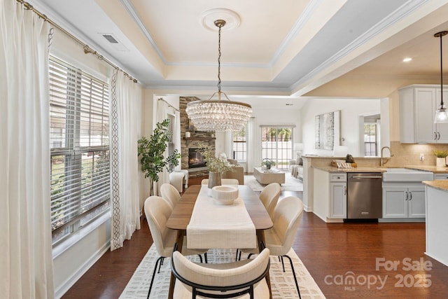 4028 Woodsmill Rd, Fort Mill, SC 29707 - dining room featuring a tray ceiling, dark wood finished floors, a chandelier, crown molding, and a fireplace