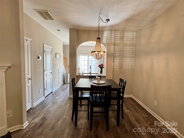 dining room featuring dark wood finished floors, a chandelier, and baseboards