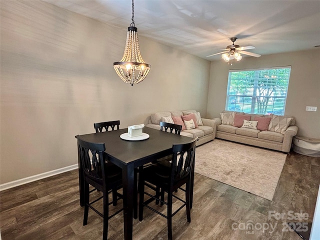 dining room featuring ceiling fan, dark wood finished floors, a chandelier, and baseboards