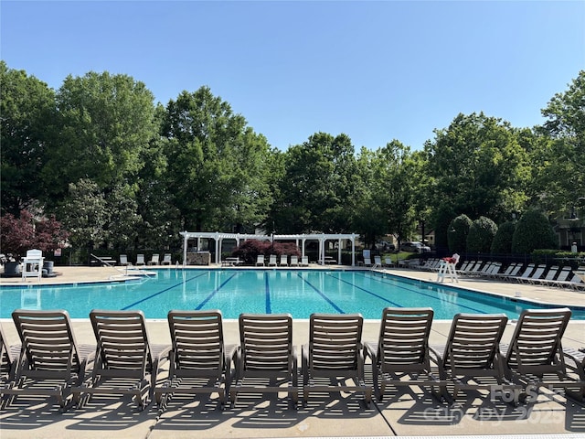 community pool with a pergola and view of scattered trees