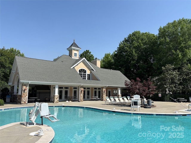 community pool with french doors, fence, and a patio