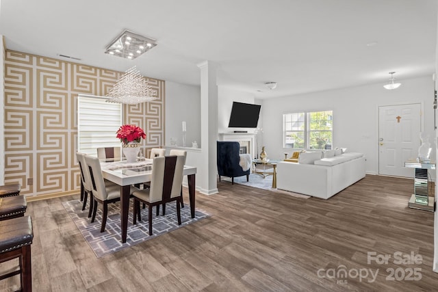 9132 Colwick Hill Ln, Charlotte, NC 28215 - dining area featuring wallpapered walls, wood finished floors, a fireplace, baseboards, and a chandelier
