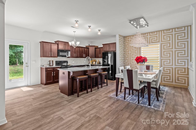 9132 Colwick Hill Ln, Charlotte, NC 28215 - dining room featuring a chandelier, wallpapered walls, baseboards, and light wood finished floors