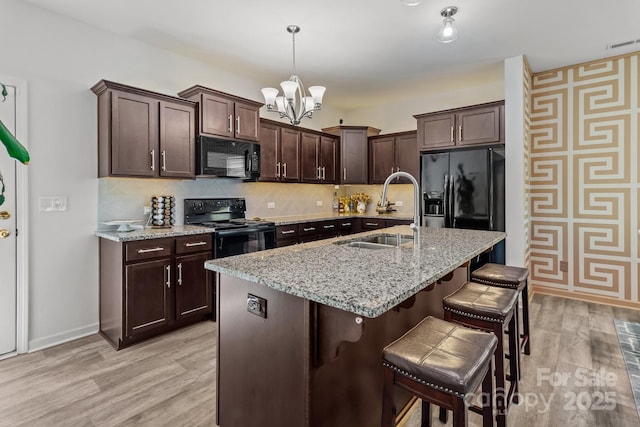 9132 Colwick Hill Ln, Charlotte, NC 28215 - kitchen with black appliances, a sink, a kitchen bar, dark brown cabinets, and a chandelier