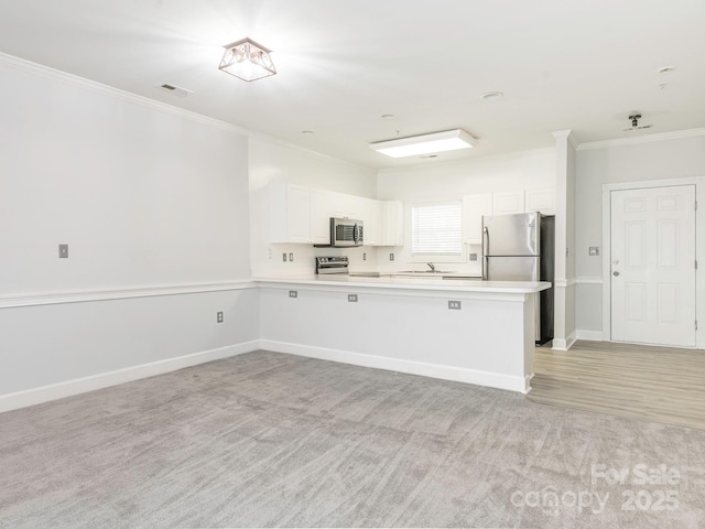 8747 Coralbell Ln, Charlotte, NC 28213 - kitchen with appliances with stainless steel finishes, ornamental molding, a peninsula, white cabinetry, and light countertops