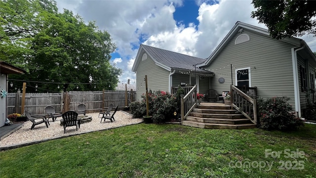 rear view of house with a deck, metal roof, a patio, and a fire pit