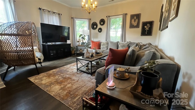living area with ornamental molding, wood finished floors, and a chandelier