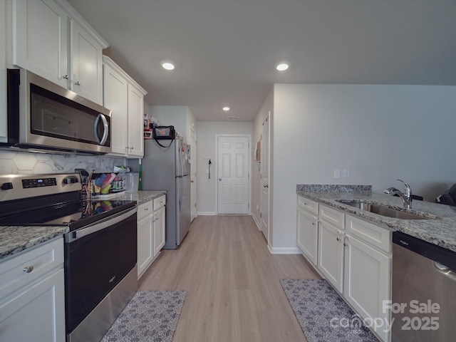 3322 Brighton Dr, Gastonia, NC 28052 - kitchen featuring appliances with stainless steel finishes, a sink, white cabinets, light wood-style flooring, and backsplash