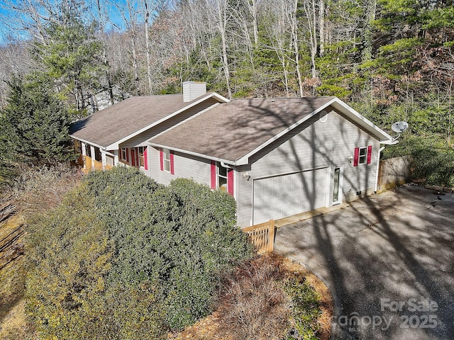 703 Cinnamon Way, Flat Rock, NC 28731 - view of side of property featuring a chimney, asphalt driveway, roof with shingles, an attached garage, and a view of trees