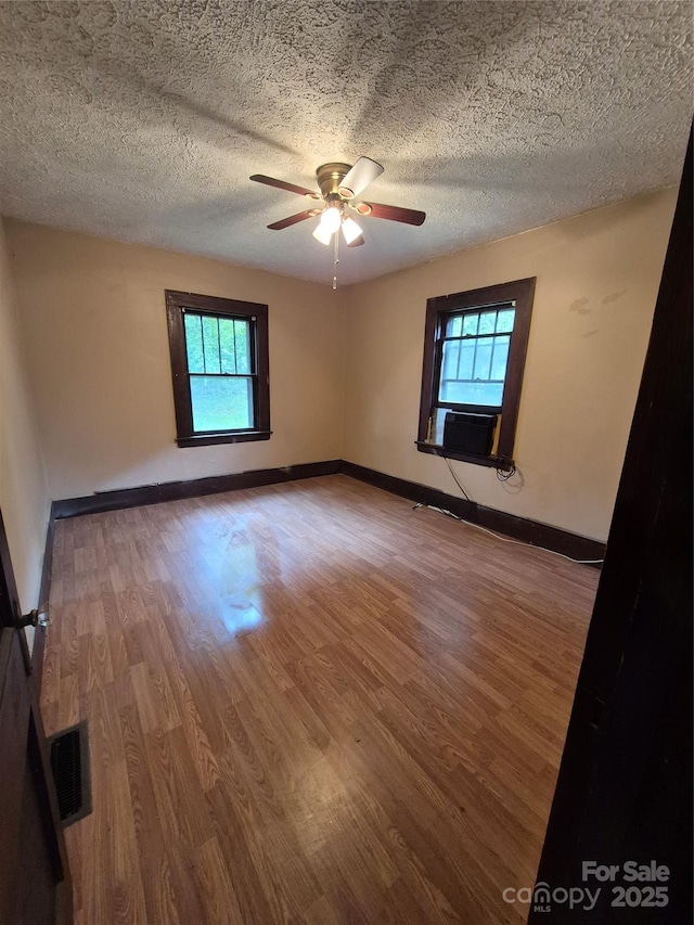 spare room featuring healthy amount of natural light, wood finished floors, a textured ceiling, and a ceiling fan