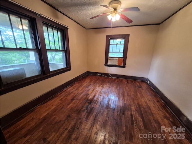 empty room with ornamental molding, dark wood finished floors, ceiling fan, baseboards, and a textured ceiling