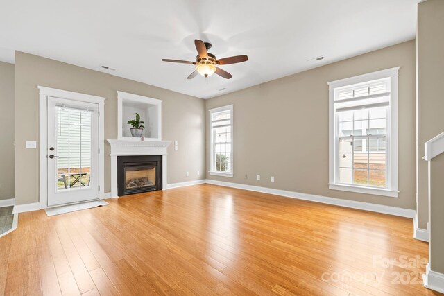 132 E Morehouse Ave, Mooresville, NC 28117 - unfurnished living room featuring light wood-type flooring, ceiling fan, a glass covered fireplace, and baseboards