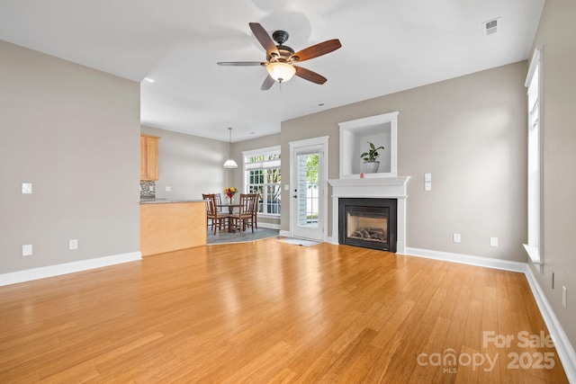 132 E Morehouse Ave, Mooresville, NC 28117 - unfurnished living room with light wood finished floors, a ceiling fan, a glass covered fireplace, and baseboards