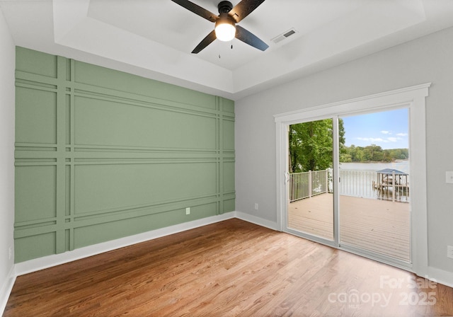 434 Breezewood Dr, Belmont, NC 28012 - empty room with wood finished floors, a tray ceiling, a ceiling fan, and a water view