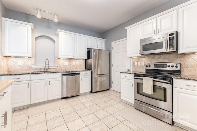 14857 Santa Lucia Dr, Charlotte, NC 28277 - kitchen featuring appliances with stainless steel finishes, a sink, white cabinetry, tasteful backsplash, and dark stone counters
