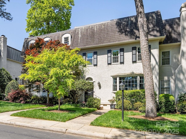 view of front of property with mansard roof and stucco siding