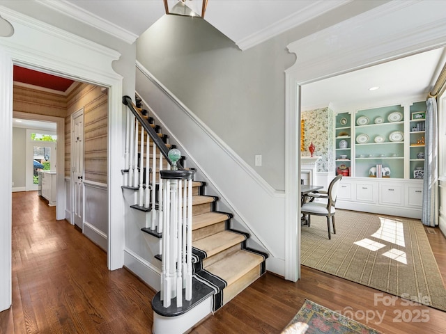 staircase featuring wood finished floors and crown molding