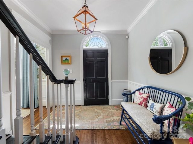 entryway featuring wood finished floors, stairs, ornamental molding, and wainscoting