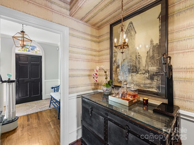 foyer entrance with a chandelier, wood finished floors, and crown molding