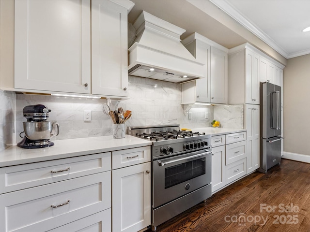 kitchen with high end appliances, premium range hood, crown molding, light countertops, and white cabinets