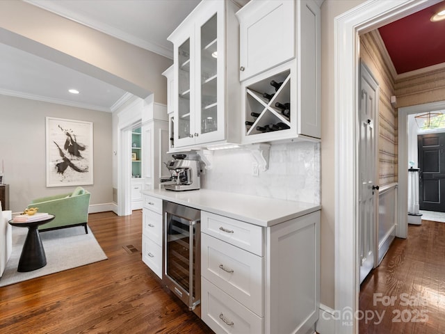 bar area with beverage cooler, ornamental molding, dark wood-style flooring, backsplash, and recessed lighting