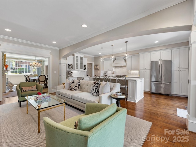 living room with arched walkways, crown molding, a chandelier, dark wood finished floors, and recessed lighting