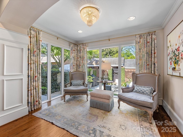 living area with crown molding, plenty of natural light, wood finished floors, a chandelier, and recessed lighting
