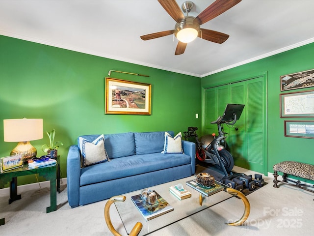 carpeted living area with a ceiling fan, ornamental molding, and baseboards
