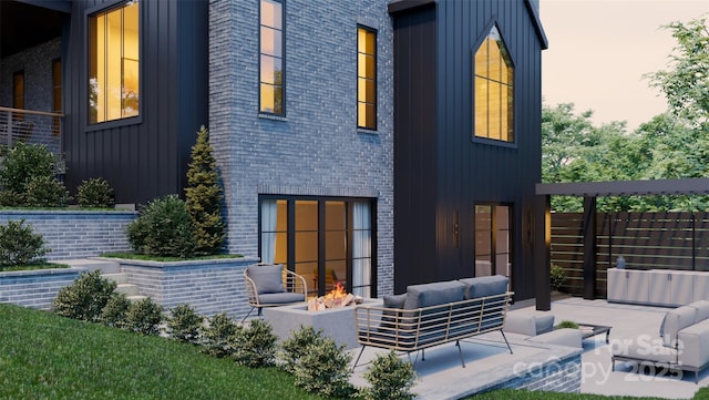 866 Concord Rd Unit 1C, Davidson, NC 28036 - back of property featuring board and batten siding, an outdoor living space with a fire pit, a patio, and brick siding