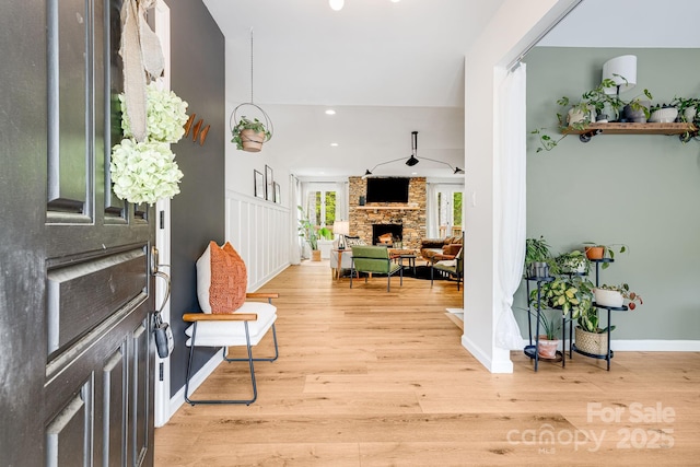 entrance foyer with a stone fireplace, light wood-style floors, baseboards, and recessed lighting