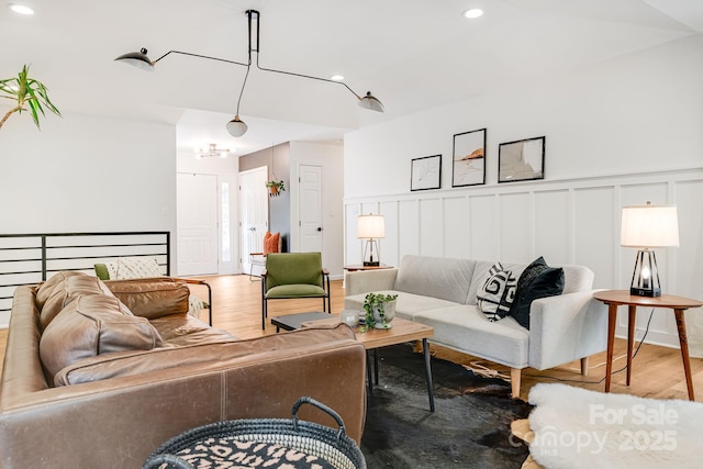 living room with a decorative wall, wood finished floors, a wainscoted wall, and recessed lighting