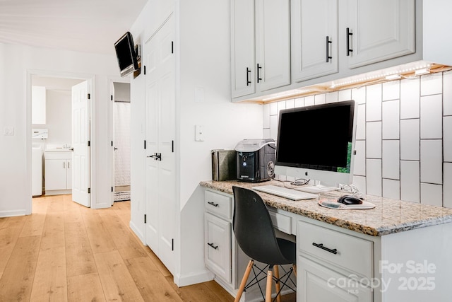 office with built in study area, light wood finished floors, washer and clothes dryer, and baseboards