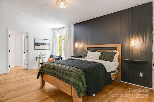 bedroom featuring wood finished floors, baseboards, a textured ceiling, and wood walls